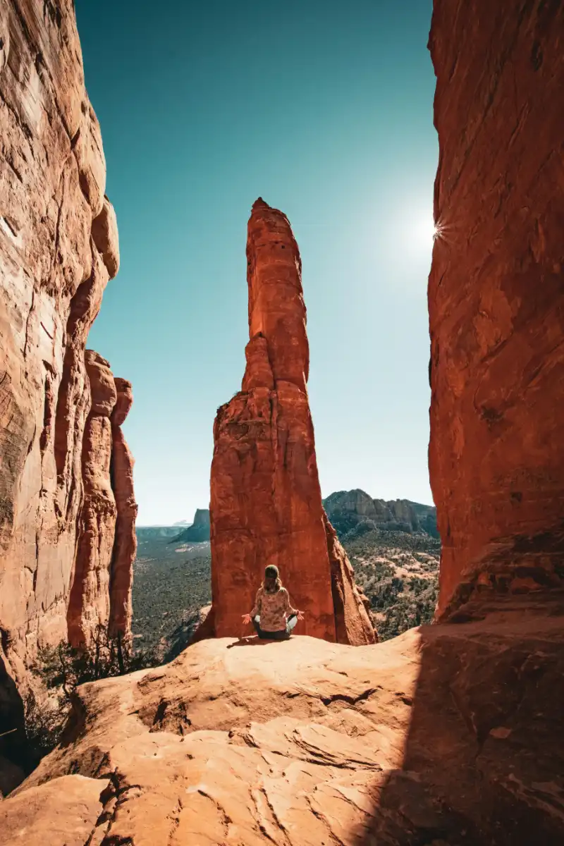 A person meditating beneath a towering Sedona rock spire
