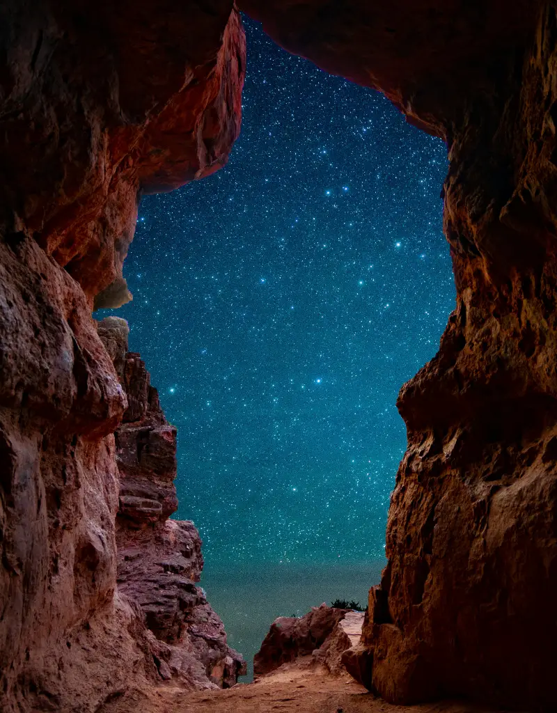 A starry night sky framed by the opening of a Sedona cave